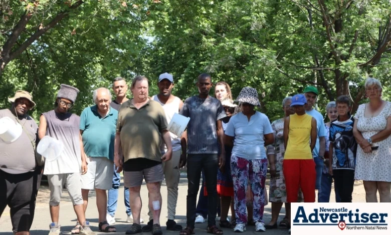 A group of Ncandu Park residents standing together on a street, some holding empty water containers